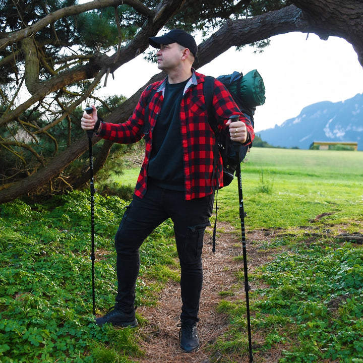 Man hiking through woodland trail using HikeWare Aluminium Hiking Poles with backpack and red check shirt