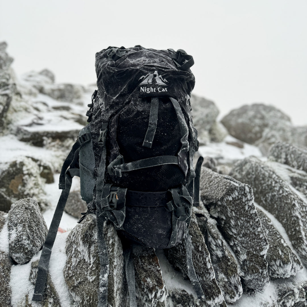 Night Cat hiking backpack resting on snow-covered rocks during a winter mountain trek