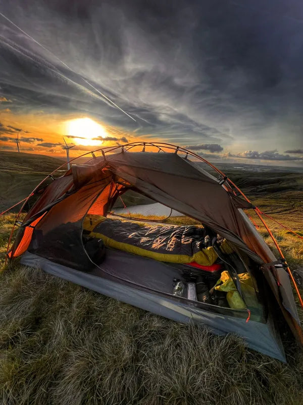 Night Cat aluminium pole tent pitched on a hillside at sunset, door open