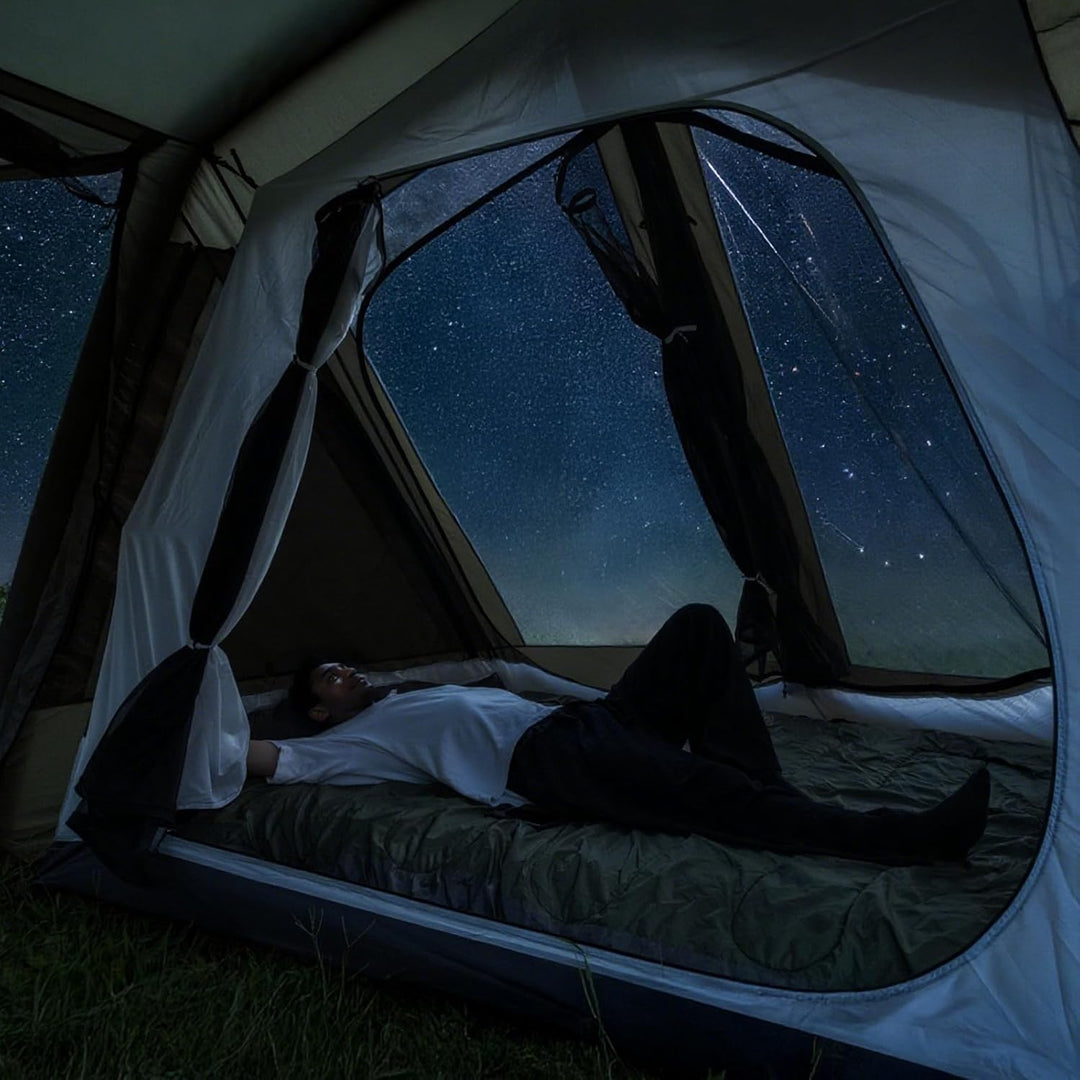 Person lying inside the Night Cat 8 person tent bedroom looking out at a starry sky