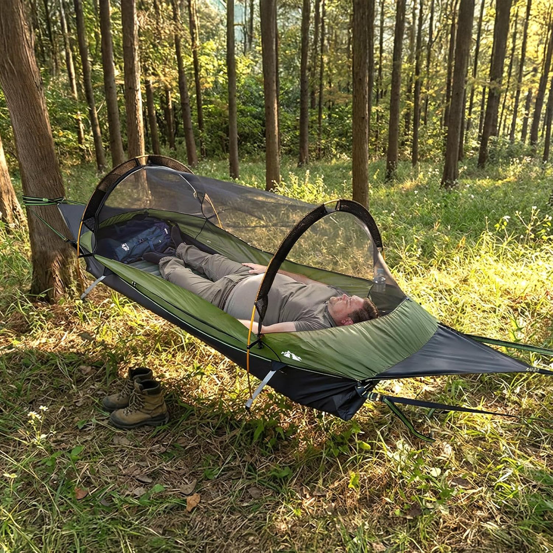 Person lying completely flat inside the Night Cat hammock tent with mosquito net, pitched between trees in a sunny forest