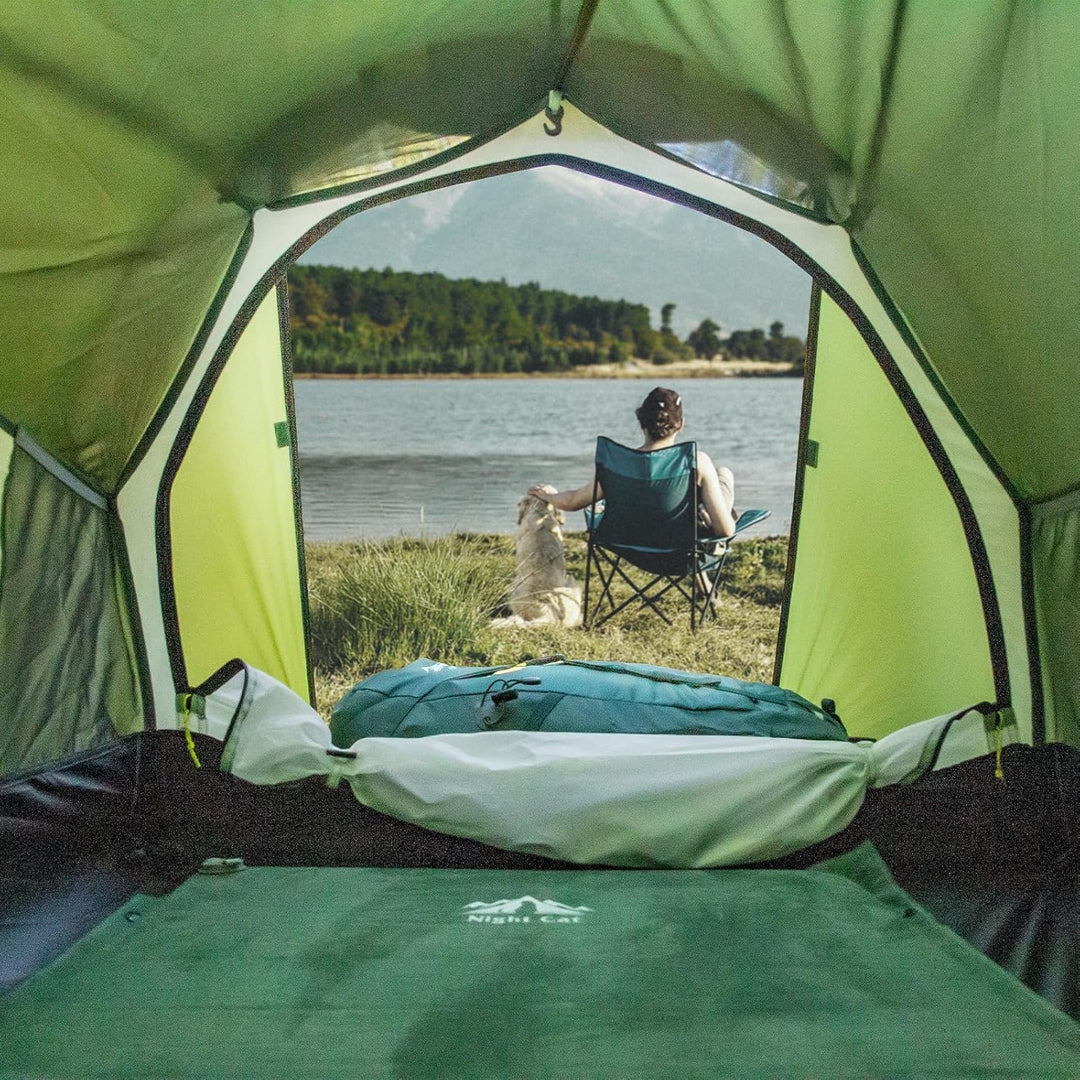 View from inside Night Cat tent facing lake with camper and dog sitting outside