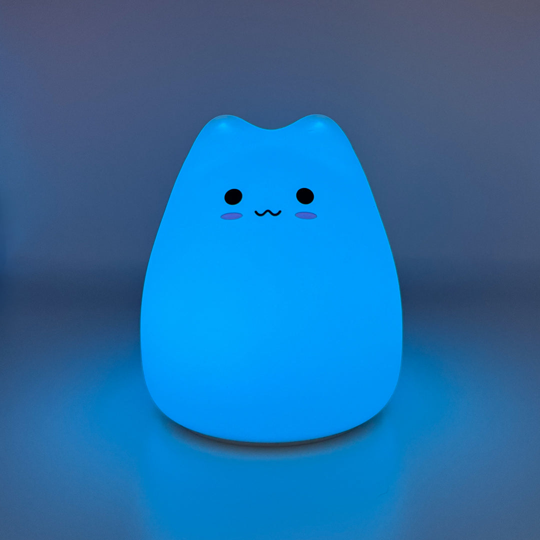 Silicone cat night light glowing blue on a dark background