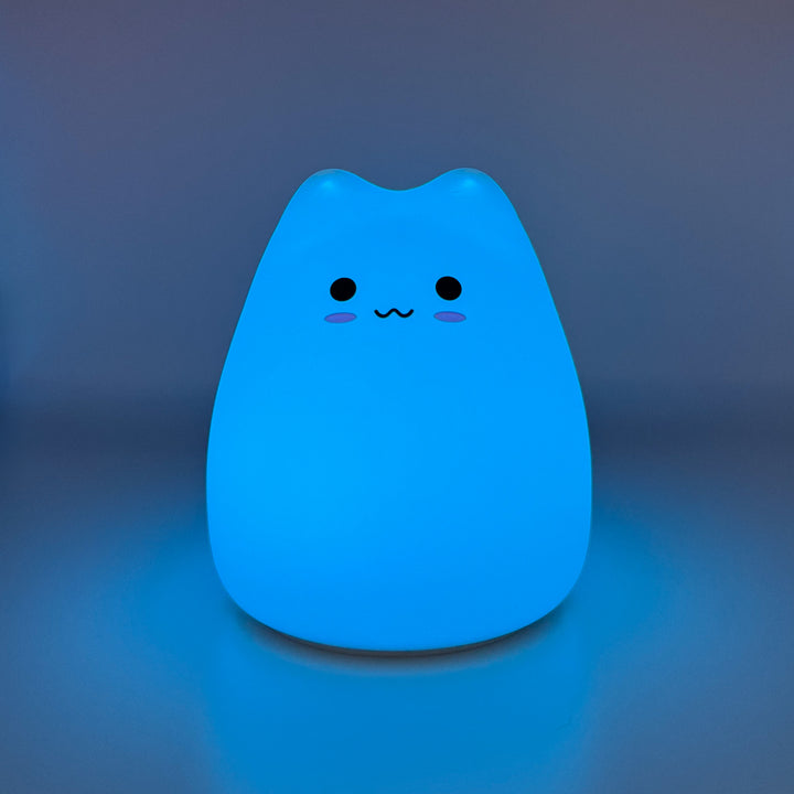 Silicone cat night light glowing blue on a dark background